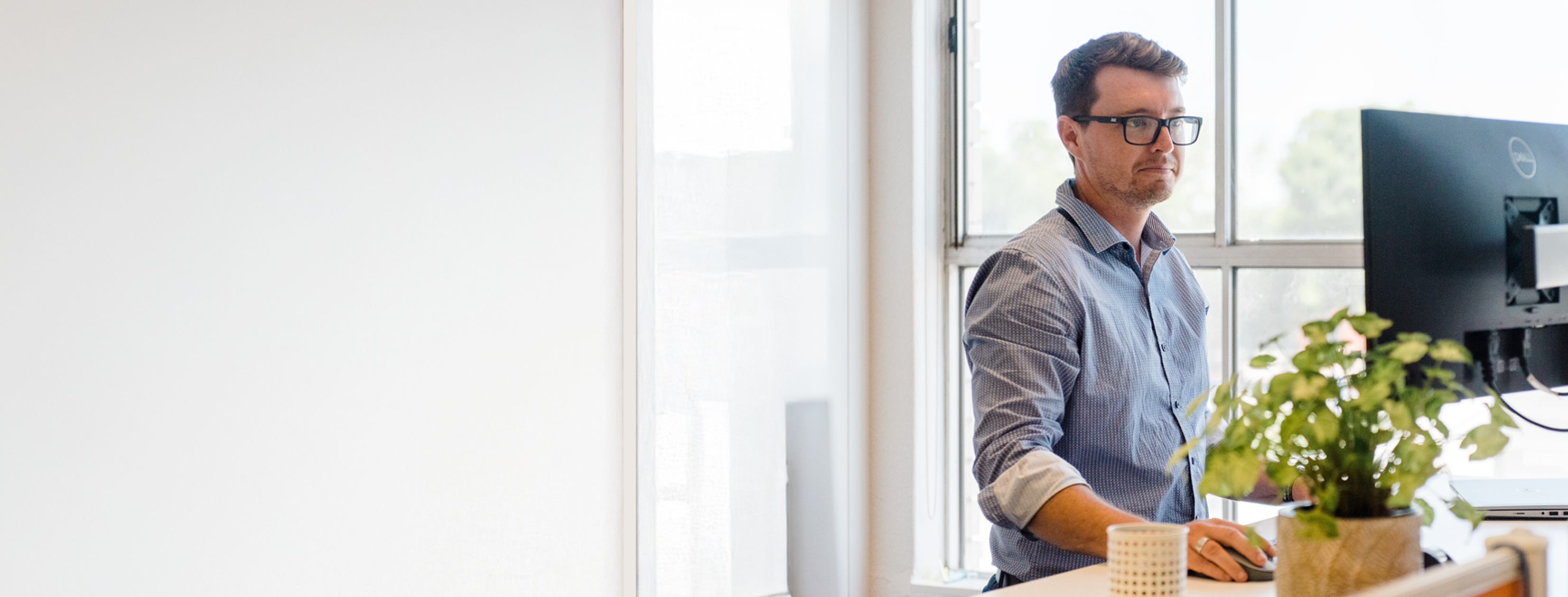 Man at stand up desk looking at computer screen.