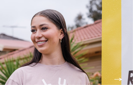 Woman standing smiling in front of sold house